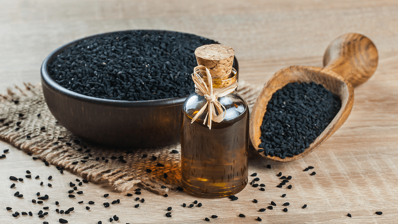 Schwarzkümmelölsamen neben einer Flasche mit dessen Öl