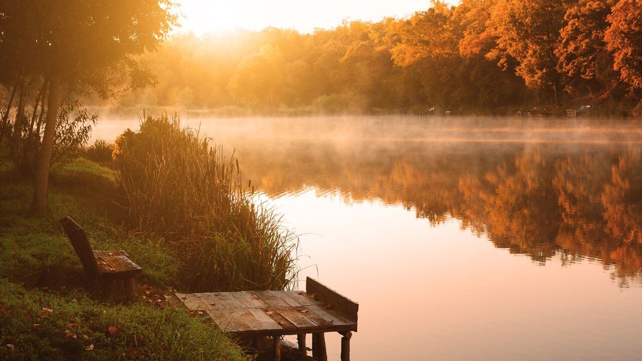 Wie findet man Ruhe und Gelassenheit in hektischen Zeiten? Friedliche Morgenszene am ruhigen See mit nebligem Wasser.