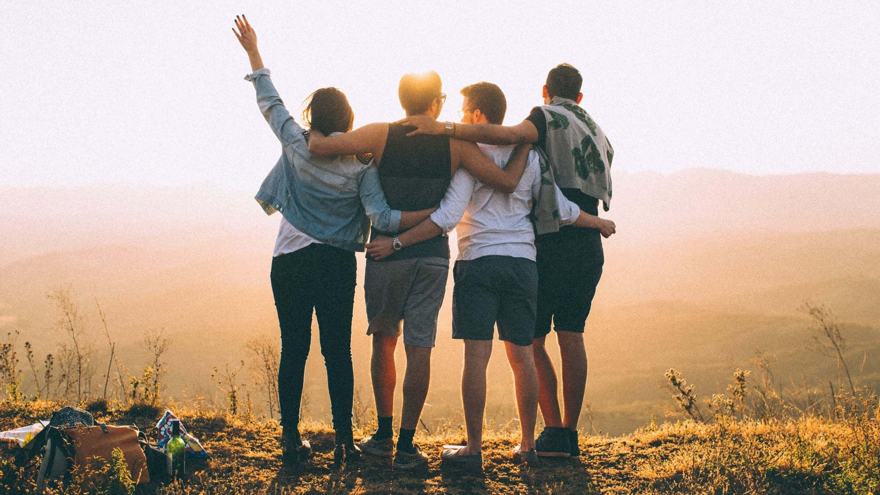 Freunde umarmen sich auf einem Berg, strahlen Freude aus und fördern die Gesundheit des Nervensystems durch Freundlichkeit.