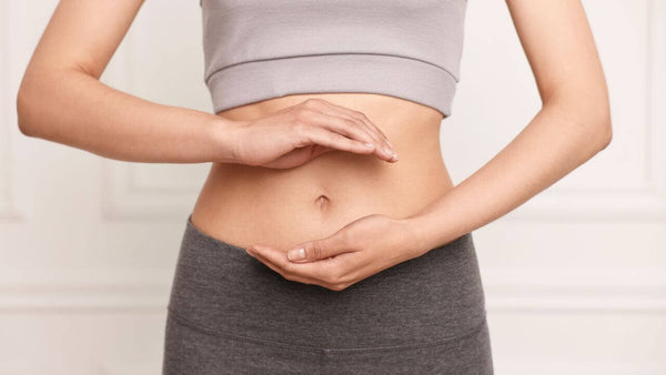 Frau zeigt auf Bauch, symbolisiert die Verdauung - Unser Körper arbeitet rund um die Uhr.