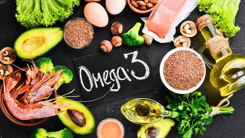 Eine Auswahl an Lebensmitteln, reich an Omega-3-Fettsäuren, darunter Avocado, Nüsse, Lachs und Garnelen.