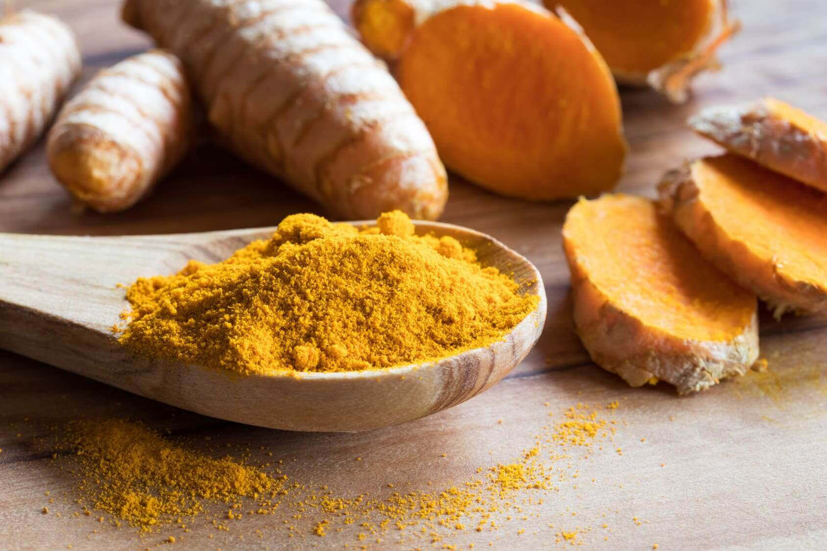 Goldene Milch: Ein Schluck Liebe für Deinen Bauch - Kurkuma in Pulverform auf einem Holzlöffel.